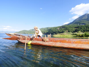 男子泛舟于青山绿水间