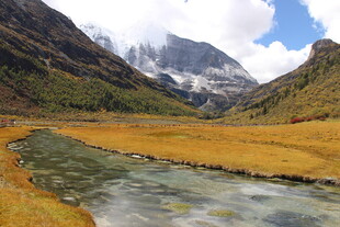 山间溪流旁的壮丽雪山景色