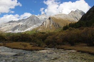 山间溪流旁的壮丽雪山景色