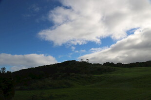 蓝天白云下的绿色山坡