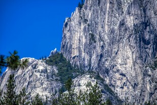巍峨山峰与蓝天绿树相映