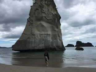 海边孤石下的漫步身影