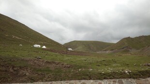 山间草地与远处小屋景色