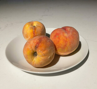 白盘上的三颗新鲜水蜜桃