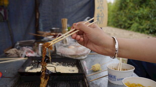 手持筷子享用户外美食