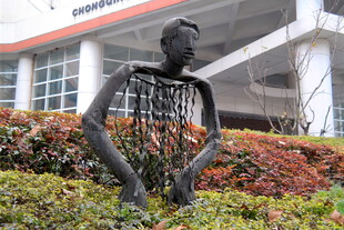 镂空人物雕塑位于绿植旁