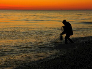 夕阳下海边的垂钓者