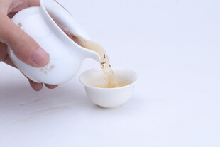 手倾白壶倒茶入小杯