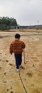 男子持棍行走于泥土地