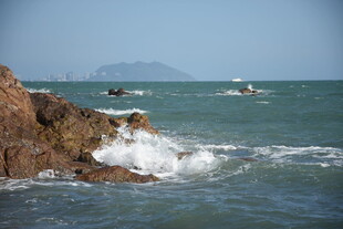 三亚海边礁石与海上船只景象