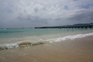 三亚海边沙滩海浪与远处桥梁