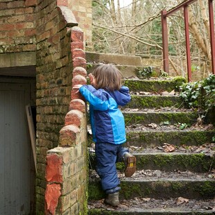 小孩在户外砖墙旁探索