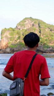 男子背身眺望海边山峦