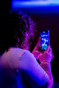 女子暗光下专注拍手机画面