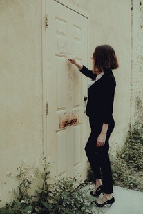 女子抬手触摸老旧墙面