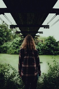 女孩背对镜头立于桥底