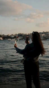 海边女子举手机赏景瞬间