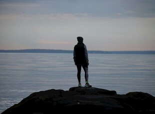 孤独身影立于海边岩石