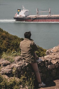 男子眺望海上航行的货船