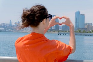 女子江边比心赏城市风景