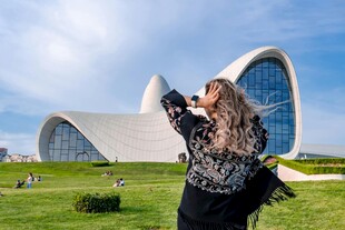 女子在现代建筑前拍照留念