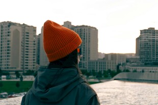 戴橙帽者眺望城市建筑群