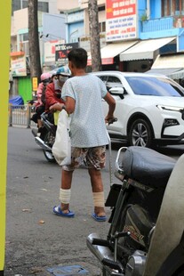 街头男子提袋站在摩托旁