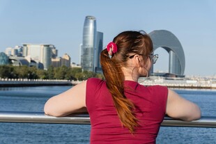 女子背身赏城市河畔风光