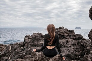 女子坐礁石眺望辽阔大海