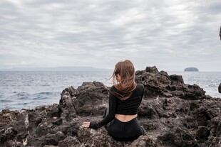 女子坐于礁石眺望大海