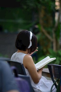 户外戴耳机阅读的女士