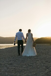 夕阳下的新婚夫妇漫步海滩