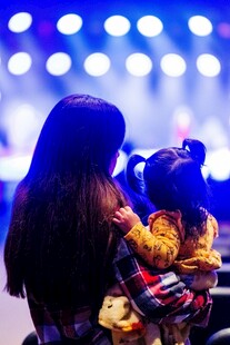母亲怀抱孩子观舞台灯光