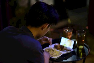 男子独自用餐看电子设备