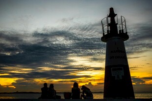 黄昏下灯塔旁的休闲人群