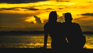 夕阳下海边的情侣剪影