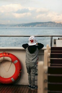 小孩船边眺望远方海景