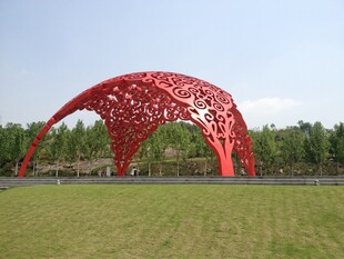 红色镂空拱形雕塑于草地