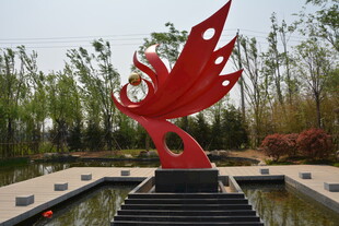 红色凤凰雕塑立于园林中