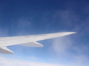 飞机机翼翱翔于蓝天白云间
