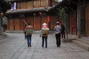 古巷中行人背着竹篓前行