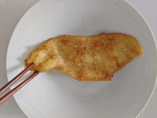 筷子夹着的煎制鸡肉