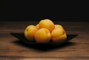 木桌上黑盘里的黄杏子