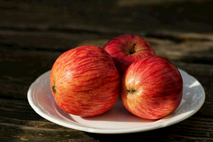 木桌上白盘里的红苹果