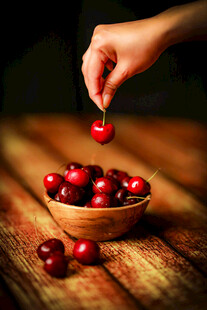 手放樱桃入木碗的温馨画面