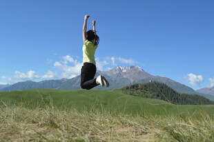 女子草原上跃起赏壮丽山景