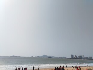 海滩上的人群与远处城市
