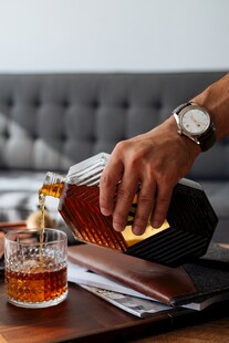 手倒威士忌于玻璃杯