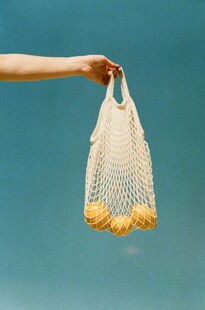 手拎网袋装满黄色水果