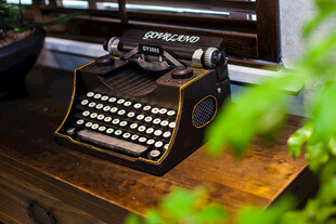 复古打字机置于木桌绿植旁